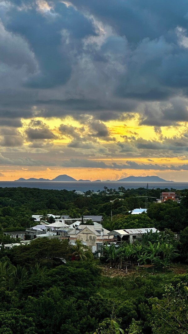 A coastal town with buildings surrounded by lush greenery and mountains in the background. - Bellevue des îles house in Sainte-Anne (Sainte-Anne)