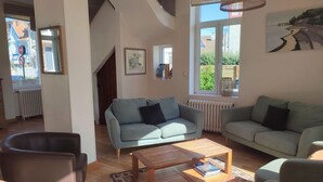 A living room with two sofas, a coffee table, and a view of the outside. - Villa Azious, 10 persons, beach side in Wimereux with parking possibility (Wimereux)