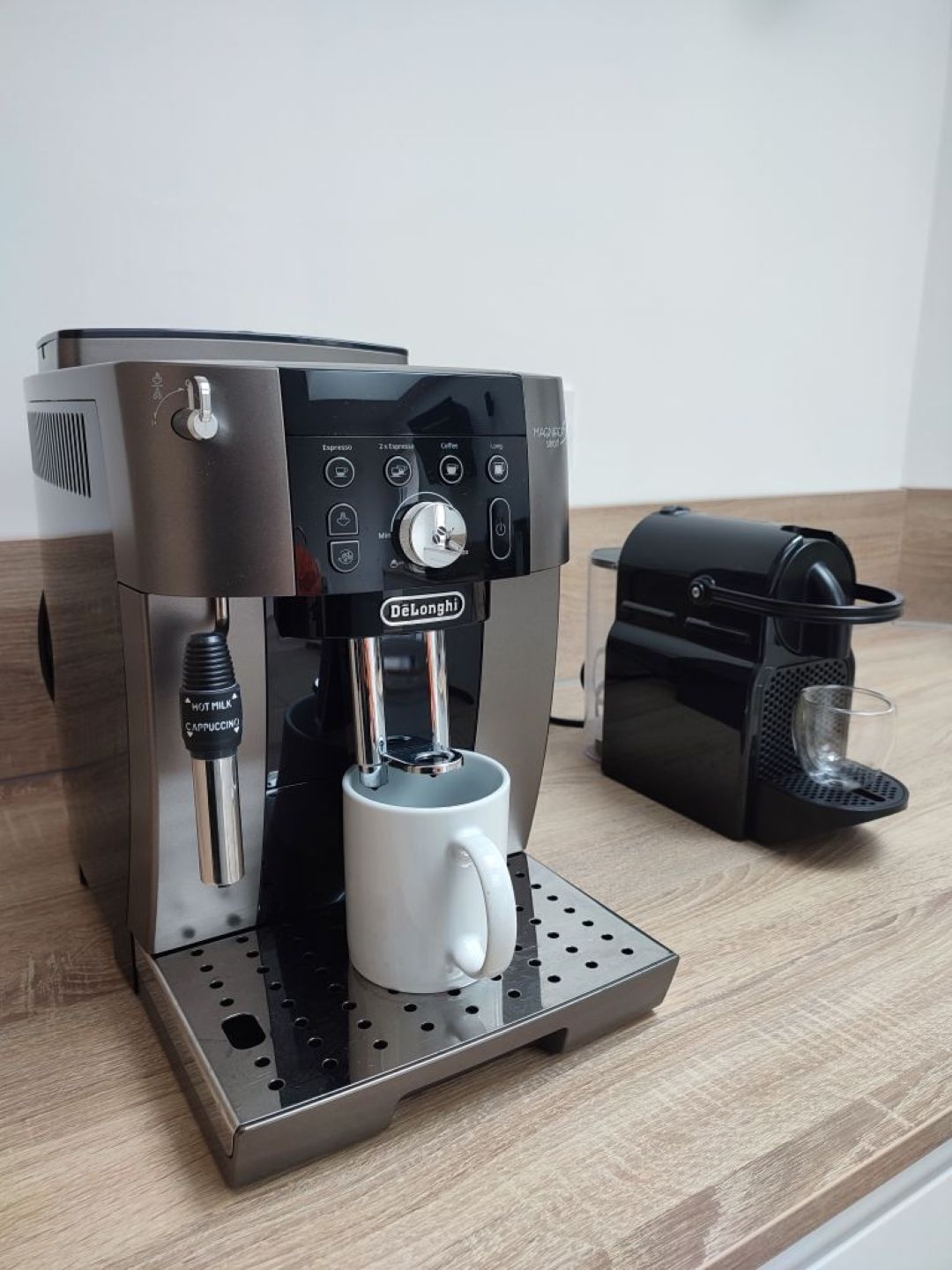 Une machine à expresso De'Longhi, dotée d'un mousseur à lait et d'un moulin à café, posée sur un plan de travail en bois.