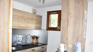 A compact kitchen with wooden cabinets, a black countertop, a coffee maker, and a kettle. - For rent: Central apartment, 3 rooms, ideal for family (Pralognan-la-Vanoise)