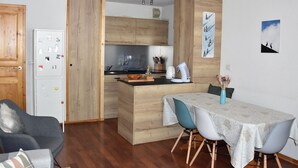 A compact living space with a kitchenette, a dining area with a table and chairs, a sofa, and a refrigerator. - For rent: Central apartment, 3 rooms, ideal for family (Pralognan-la-Vanoise)