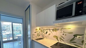 A modern kitchen with a microwave, sink, and a view of an outdoor balcony with tables and chairs. - Studio for 4 people with sea view - Hyères Port (HYERES PLAGE)