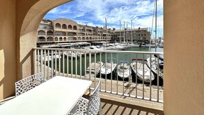 A balcony with a view of a marina, featuring boats and a building with arched balconies. - Studio for 4 people with sea view - Hyères Port (HYERES PLAGE)
