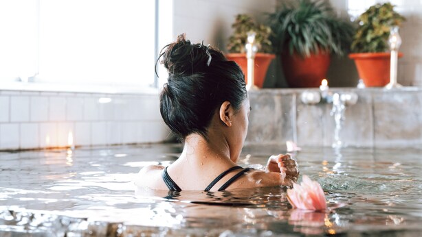 A person in a hot tub with a tiled wall and potted plants in the background. - Lumbini Hokke Hotel (Sauraha Pharsatikar)