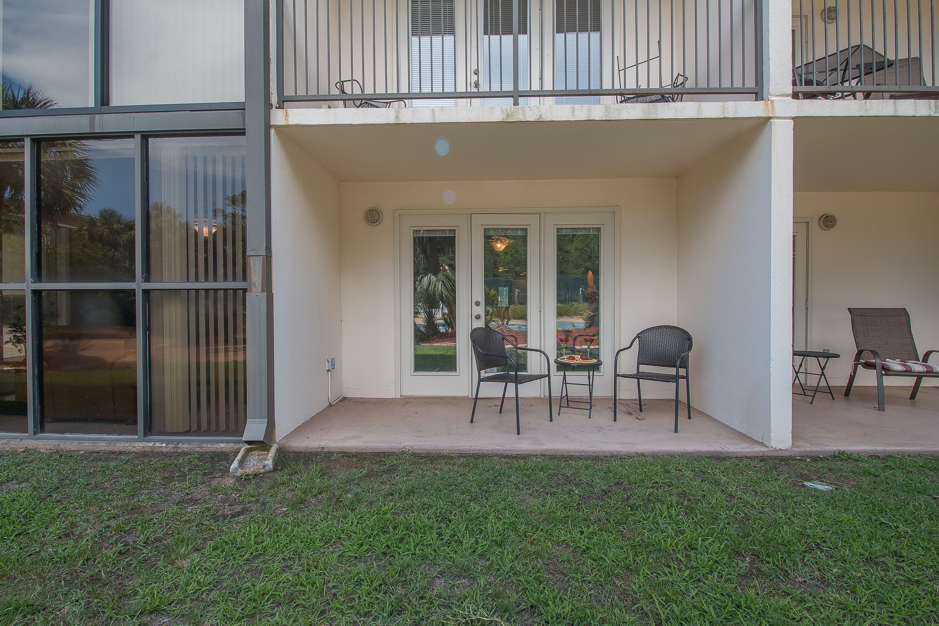 Un bâtiment à deux étages doté d’un patio couvert comprenant deux chaises et une petite table.
