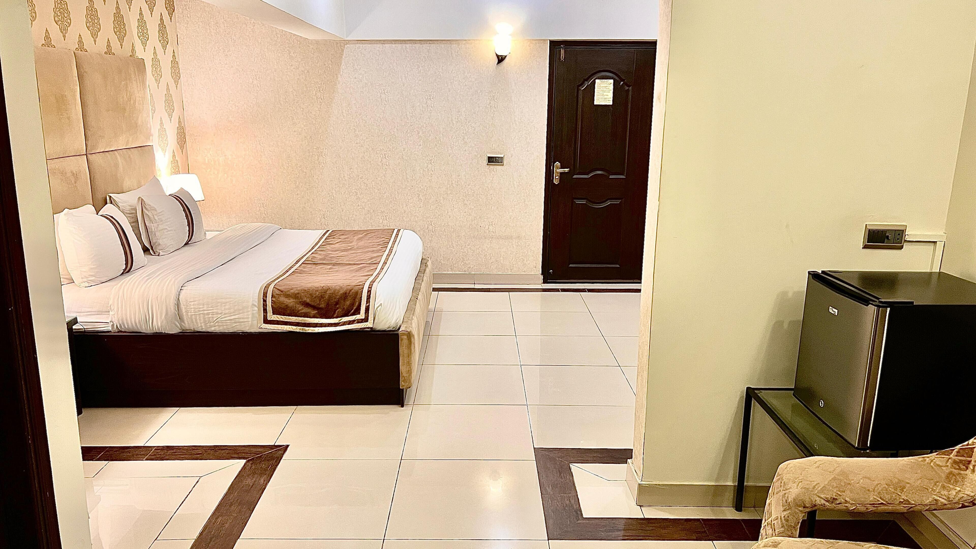 A hotel room with a bed, a television, a door, and a small table.