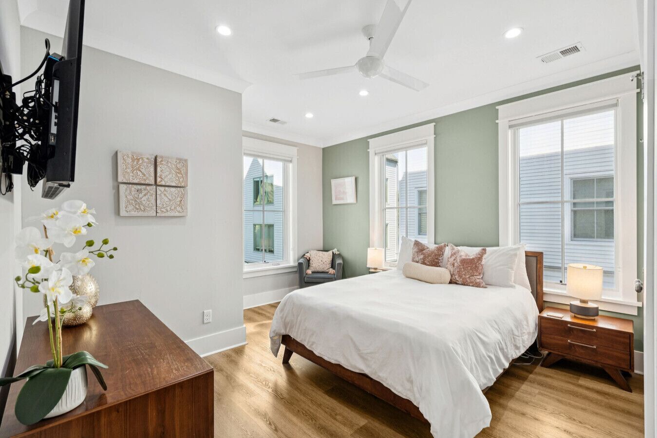 A bedroom with a large bed, a desk, a chair, and a window with blinds.