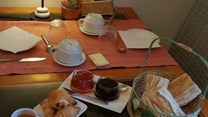 A breakfast table with croissants, jam, tea, and a basket of bread. - Manoir De Tireveste (Lesperon)