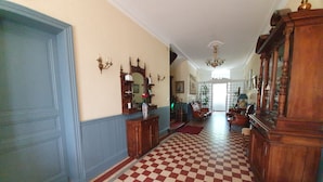 A hallway with a checkered floor, wooden furniture, and a blue door. - Manoir De Tireveste (Lesperon)