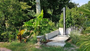 A garden pathway with a concrete bench, surrounded by lush greenery and a variety of plants. - Manoir De Tireveste (Lesperon)