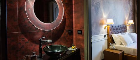 A modern bathroom with a round mirror, a black sink, and two small glasses on the counter.