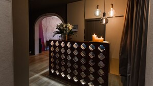 A reception area with a decorative wall, a vase with flowers, and a mirror.