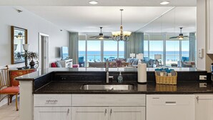 Une cuisine moderne dotée d’un grand îlot central, d’un évier intégré et offrant une vue sur l’océan.