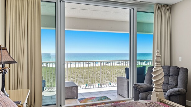 Une chambre d’hôtel dotée d’une grande porte-fenêtre coulissante donnant sur un balcon avec vue sur la plage.