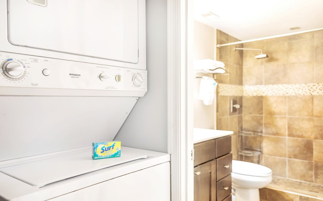 A modern bathroom with a built-in washing machine, a toilet, and a shower area.