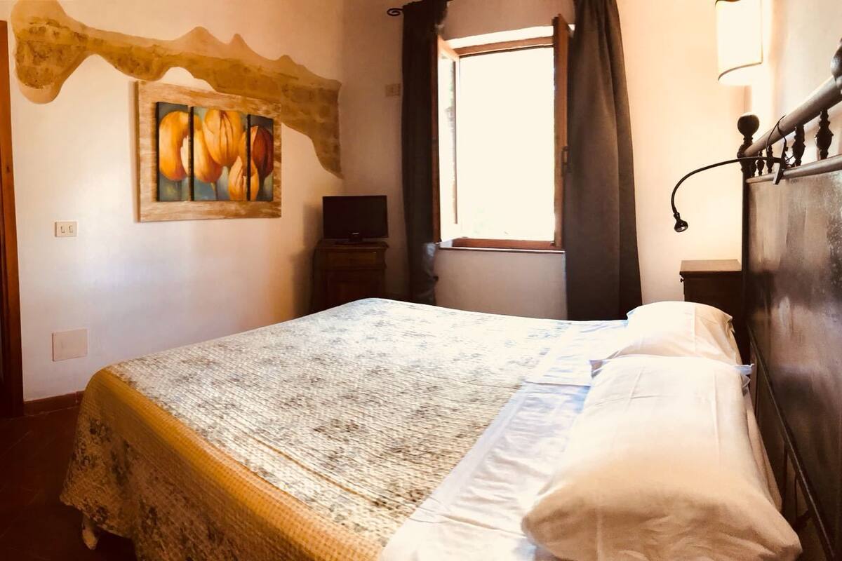 Une chambre à coucher avec un lit, un tableau, une fenêtre et une tête de lit en bois.