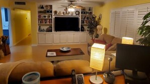 Ein Wohnzimmer mit einer Couch, einem Couchtisch, einem Fernseher und einem Bücherregal.