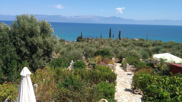 A stone pathway leading to a scenic view of the sea with mountains in the background. - Βίλα Μιχάλης  πανόραμα (Kombi)