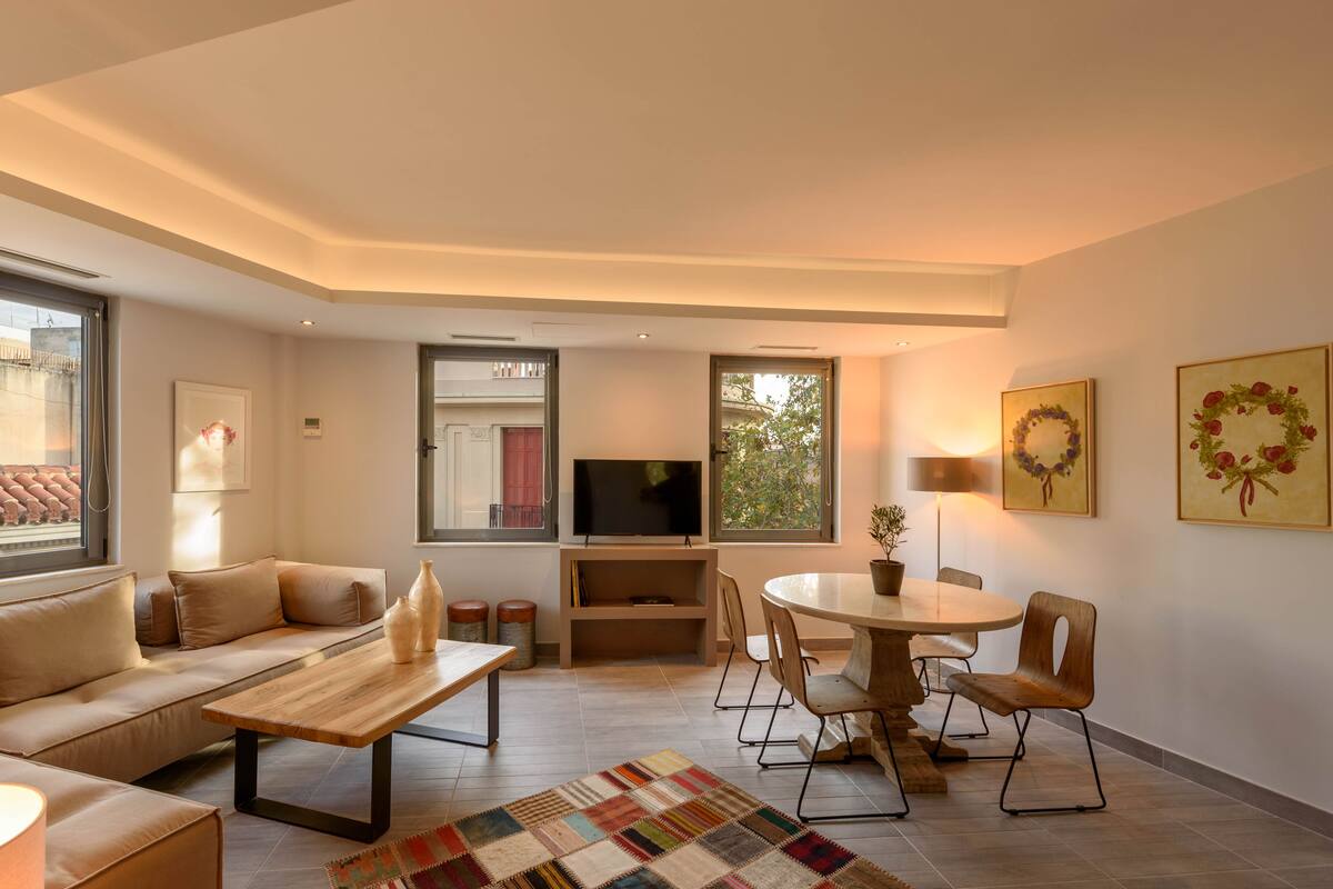 A modern living room with a sofa, coffee table, TV, and dining area.
