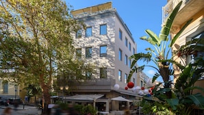 A building with multiple floors, outdoor seating, and potted plants. - Fos Residential Apartments (Athens)