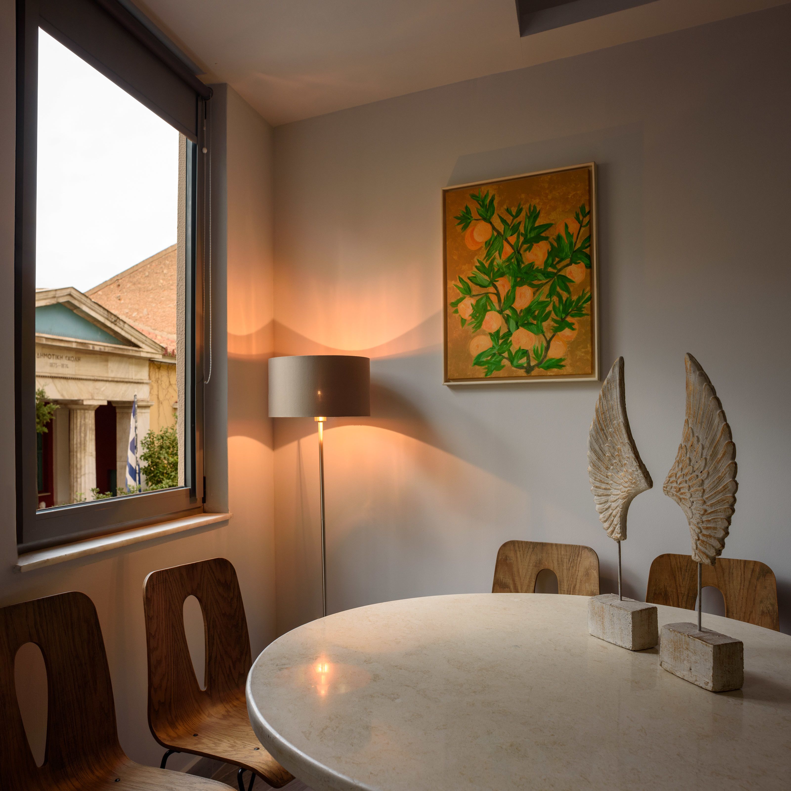 Un'area pranzo con un tavolo rotondo, sedie, una lampada e un quadro.