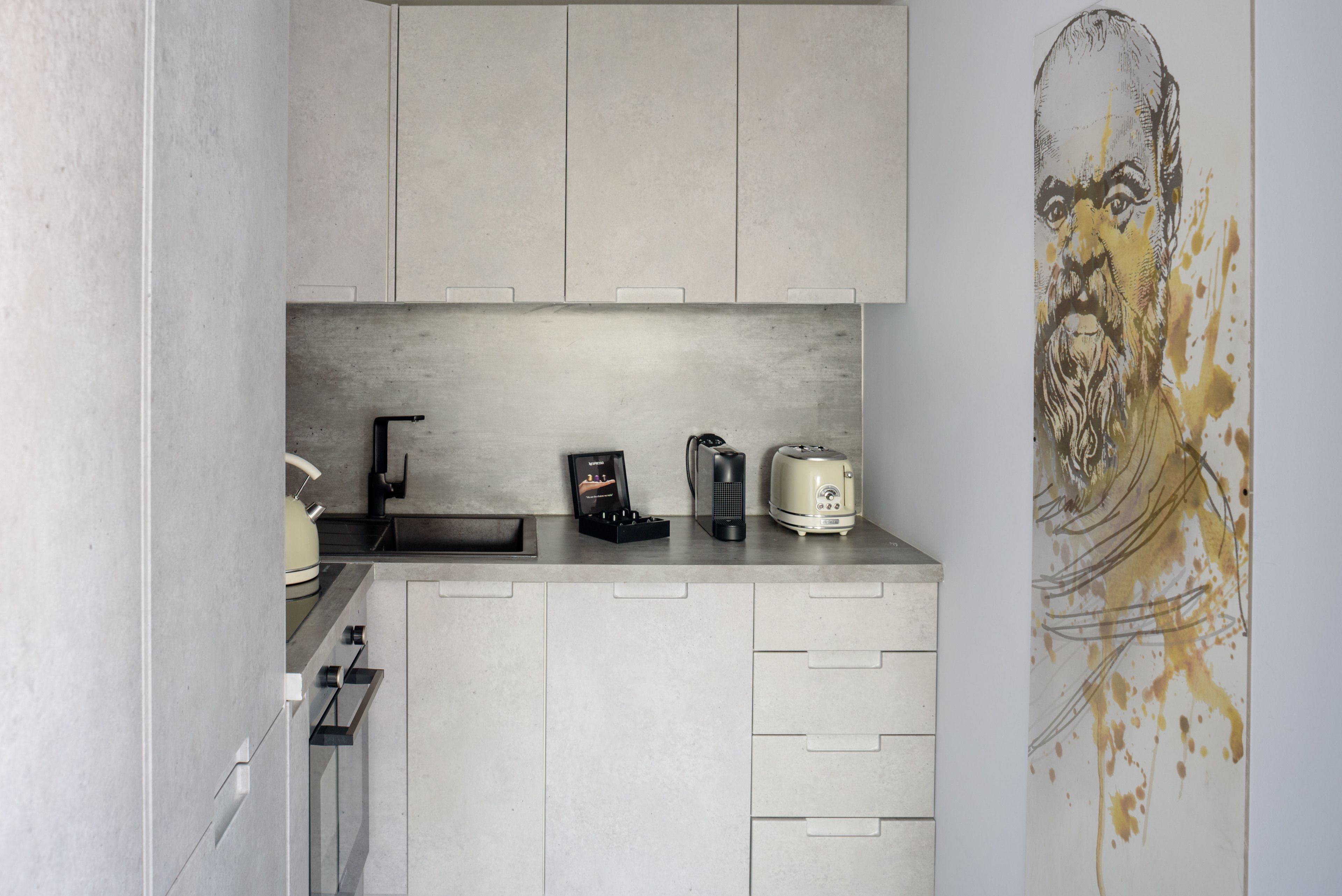 A modern kitchen with grey cabinets, a kettle, a coffee maker, and a toaster.