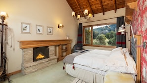 Un dormitorio acogedor con chimenea, una cama, un ventanal con vistas al exterior y un candelabro.