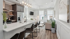 Een moderne keuken met een groot eiland, inbouwapparatuur en een moderne lamp.