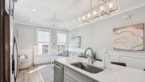Een moderne keuken met een centraal eiland, roestvrijstalen apparatuur en een hanglamp.