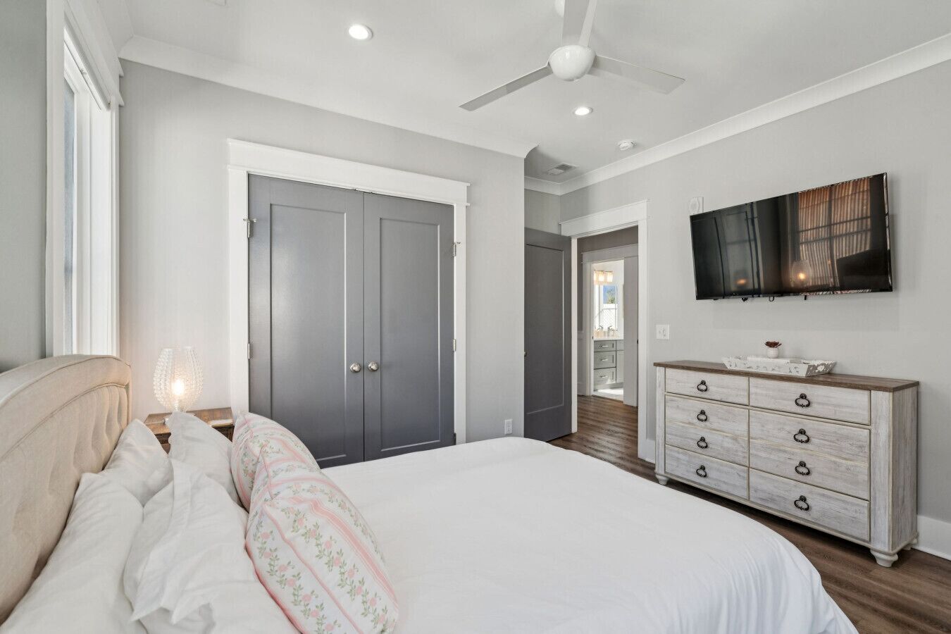 A bedroom with a bed, dresser, and a ceiling fan.