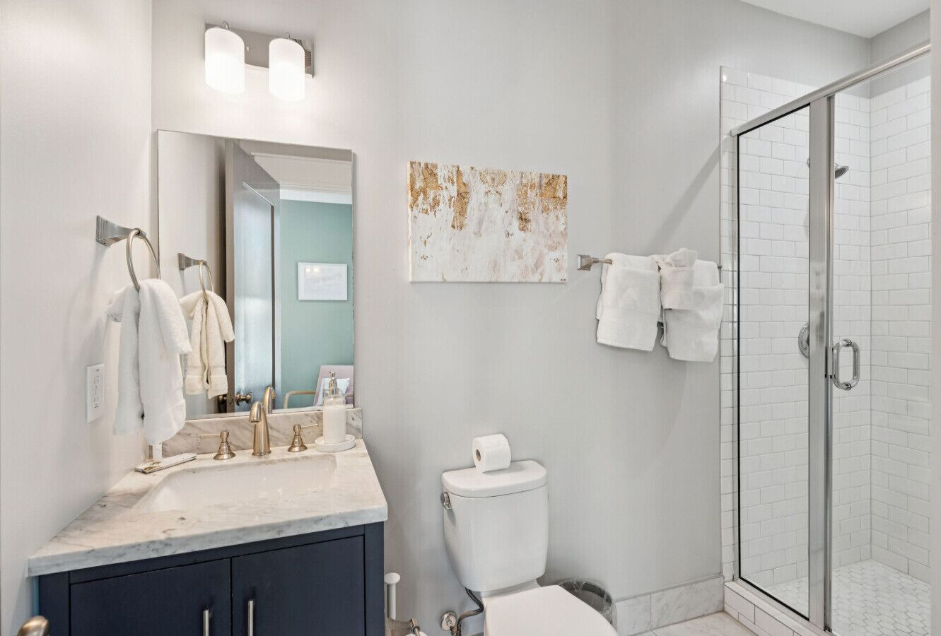 Une salle de bain moderne avec un lavabo en marbre, une cabine de douche en verre et des toilettes.