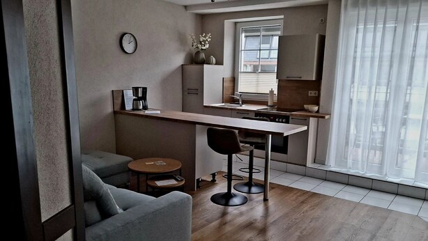 A modern kitchen with a wooden countertop, a built-in oven, and a window with blinds. - Zum Weingutsmuseum (Cochem)