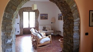 A room with a stone archway leading to a living area with a sofa, chairs, and a table.