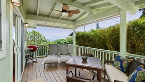 Eine überdachte Veranda mit Tisch, Stühlen und Deckenventilator.