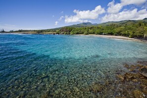 A clear coastal view with a beach and mountains in the background.