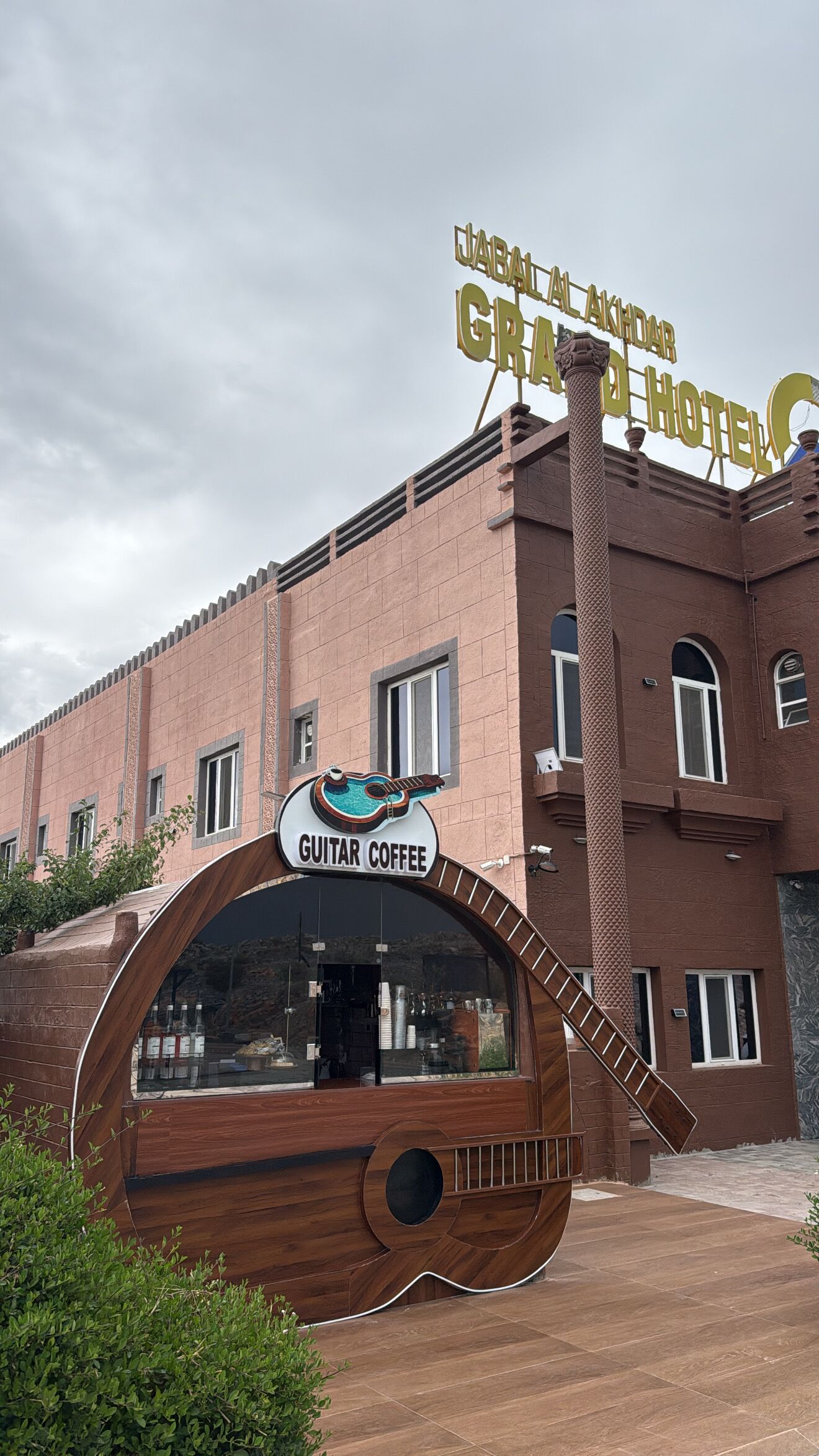 Un edificio con un cartel que dice 'Guitar Coffee' y 'Jabal Al Akhdar Hotel'.