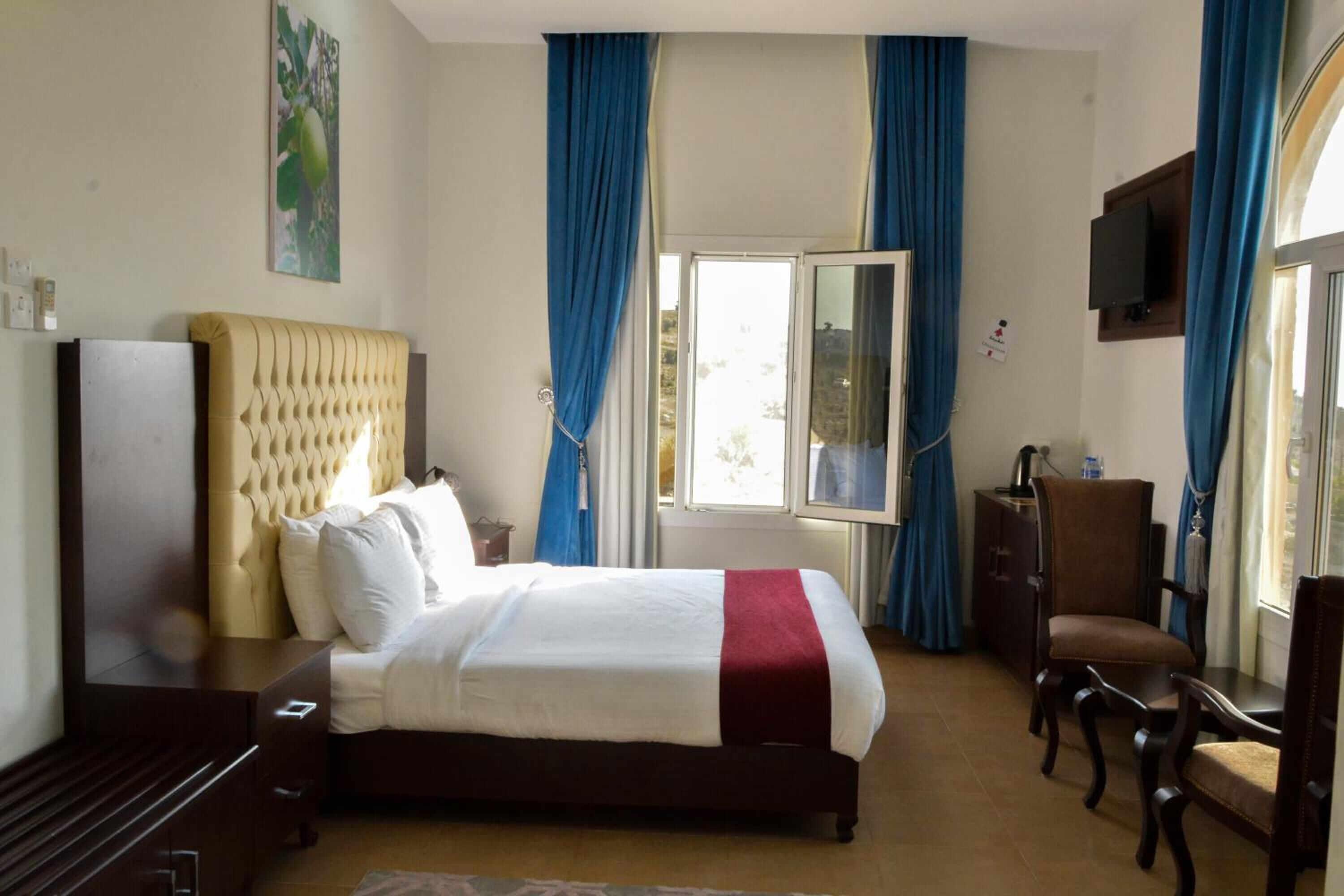 Habitación de hotel con una cama grande, un escritorio, una silla y un televisor en la pared.