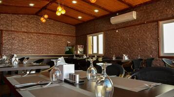 A restaurant with brick walls, wooden ceiling, and hanging light fixtures. Tables are set with cutlery and glassware.