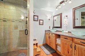 A bathroom with a glass shower enclosure, wooden vanity with two sinks, and a large mirror. - 'View & Far Between' Cozy Mountain Home w/ hot tub (Ashe County)
