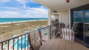 Un balcon avec vue sur une plage et une piscine.