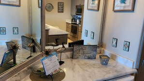 A kitchen with a marble countertop, stainless steel appliances, and a large mirror.