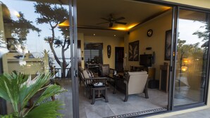 A modern living room with a glass door, a ceiling fan, and a dining area with chairs and a table.