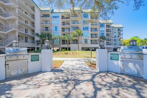 A multi-story hotel with balconies, a paved entrance, and outdoor grills. - Ocean Views at Villamare 1404 in Palmetto Dunes, Right on the Beach! (Hilton Head Island)