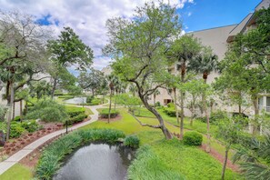 A landscaped courtyard with a pond, pathways, and mature trees.