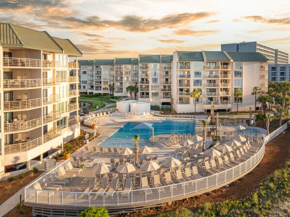 A hotel with multiple balconies, a central pool, and sun loungers arranged around the pool.