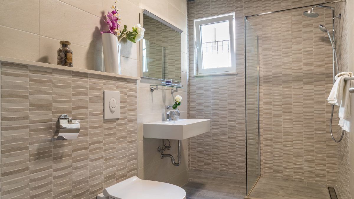 A modern bathroom with a glass shower enclosure, a white sink, and a toilet.