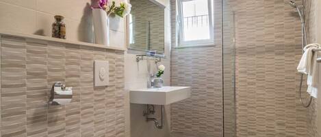 A modern bathroom with a glass shower enclosure, a white sink, and a toilet.