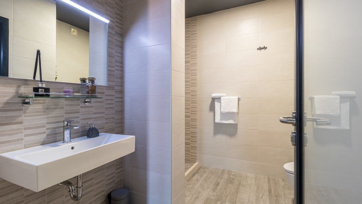 Un baño moderno con lavamanos, espejo y zona de ducha.