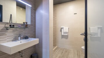 Un baño moderno con lavamanos, espejo y zona de ducha.
