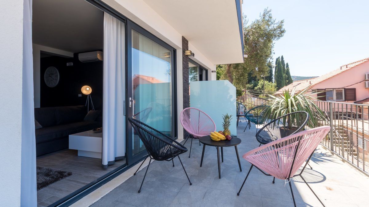 Varanda externa com cadeiras modernas, uma mesa com frutas e vista da região ao redor.